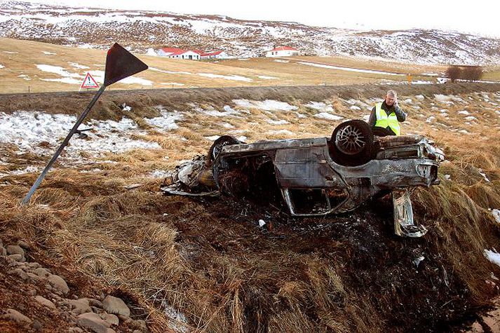 Lögreglumenn á vettvangi. Mikill eldur kom upp í bifreiðinni eftir að hún hafnaði utan vegar og tókst vegfarendum sem komu að slysinu ekki að slökkva eldinn með handslökkvitæki.