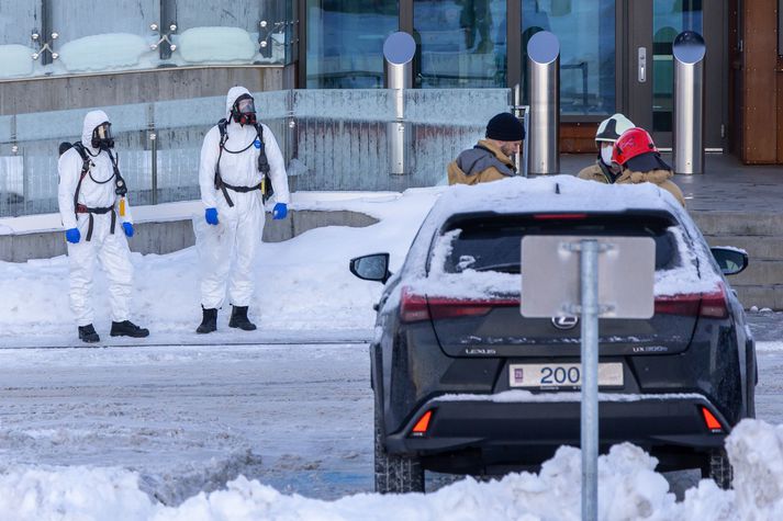 Tveir slökkviliðsmenn klæddir í hlífðarbúnað og með gasgrímur við sendiráðið í dag.