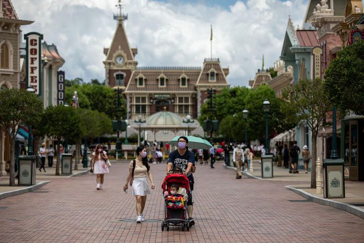 Grímuklæddir gestir Disneyland-skemmtigarðsins í Hong Kong. Honum verður lokað frá og með morgundeginum vegna fjölgunar nýrra smita í borgríkinu.