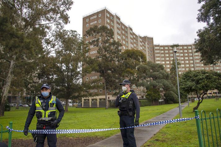 Lögregluþjónar gæta þess að enginn fari inn í þessa blokk í Melbourne, þar sem allir íbúar eru í sóttkví.