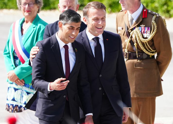 Sunak og Macron glaðbeittir við komu á söguslóðir seinni heimsstyrjaldar í Normandí.