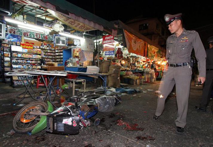 Lögreglumaður skoðar svæðið þar sem ein af sprengjunum í Bangkok sprakk.