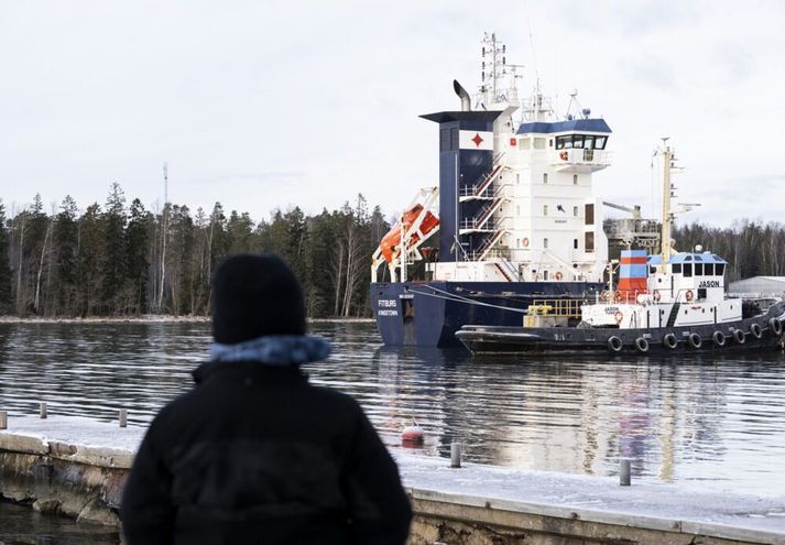 Finnskt skip fylgir flutningaskipinu Fitburg til hafnar í Kantvik 1. janúar. Fitburg dró akkeri langa leið eftir hafsbotninum og rauf tvo fjarskipasæstrengi.