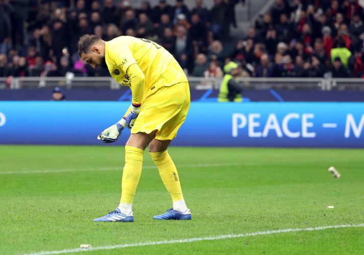 Gianluigi Donnarumma tekur upp platpeningana sem kastað var í hann.