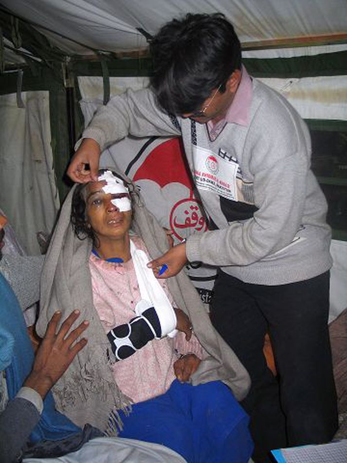 Í sárum. Hugað að sárum konu eftir rútuslys í Muzaffarabad í Pakistan í gær.