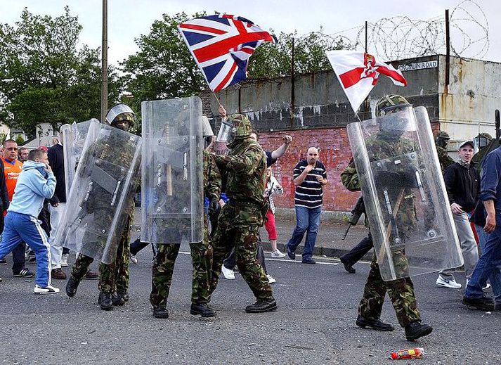 Sambandssinnar veifa fána Bretlands og Norður-Írlands þegar þeir ganga í fylgd hermanna sem reyna að verja þá gegn grjótkasti frá þjóðernis­sinnum í Belfast árið 2003.