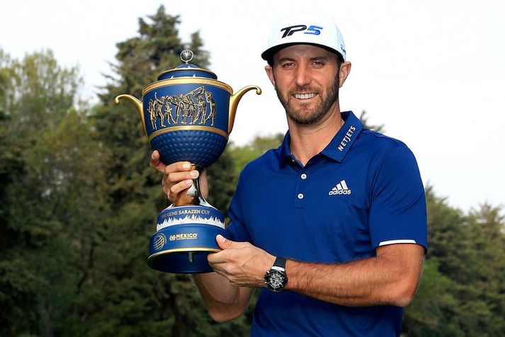 Dustin Johnson með sigurlaunin í nótt.