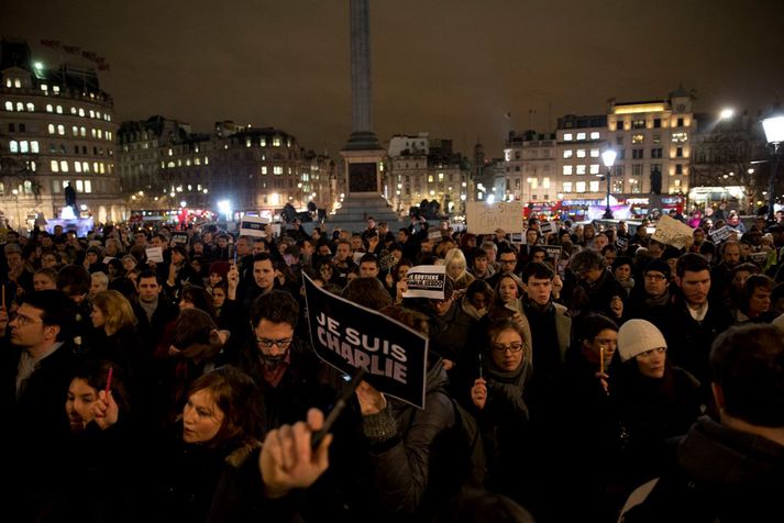 Fólk heldur ýmist á skiltum merktum "Je suis Charlie" eða "Ég er Charlie", farsímum, pennum og kertaljósum.