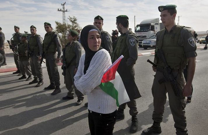 Palestínsk kona með fána þjóðar sinnar þar sem ísraelskir hermenn höfðu lokað vegiá Vesturbakkanum í vikunni.