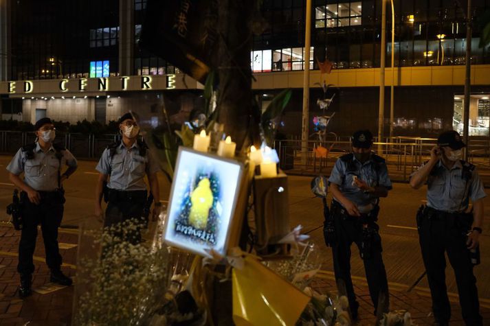 Lögreglumenn í Hong Kong standa vakt við minningarskjöld um mótmælandann.