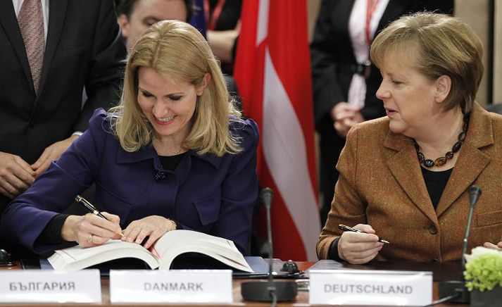Helle Thorning-Schmidt, forsætisráðherra Danmerkur, sem nú fer með formennsku í ráði Evrópusambandsins, undirritar samning um fjármálabandalag. Angela Merkel Þýskalandskanslari bíður eftir að röðin komi að sér.
nordicphotos/AFP