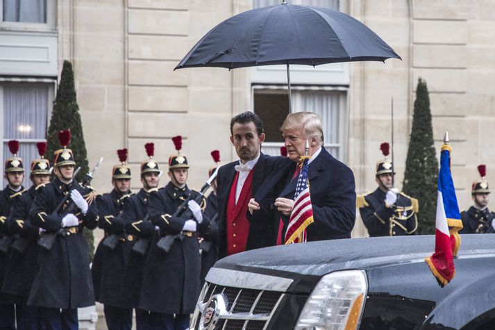 Donald Trump undir regnhlíf fyrir utan aðsetur Frakklandsforseta í dag.