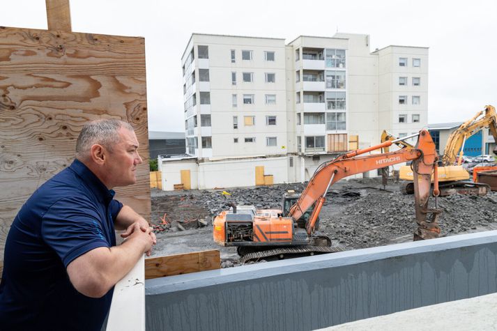 Sigsteinn Sigurbergsson við hlið viðarplötunnar sem er beint fyrir framan íbúðina hans fyrir framan framkvæmdir við Fannborgarreitinn. 