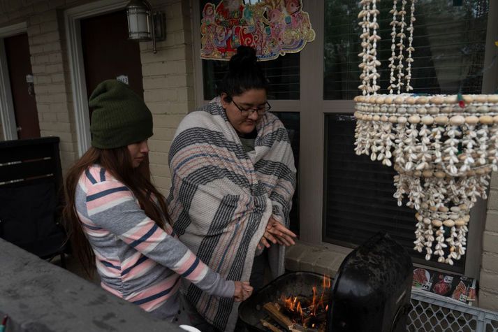 Karla Perez og Esperanza Gonzalez hlýja sér yfir grillinu á heimili sínu í Texas sem er án rafmagns vegna kulda og snjóa.