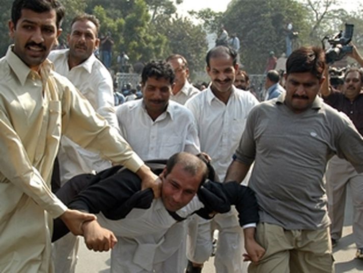 Óeinkennisklæddir lögreglumenn handtaka lögfræðing í mótmælum í Lahore í dag.