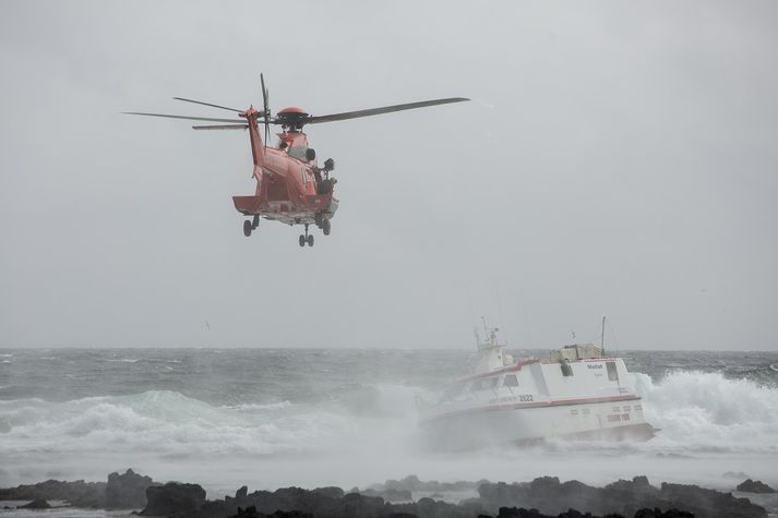 Myndin sýnir þyrlu Landhelgisgæslunnar fljúga að bát sem strandað hefur.