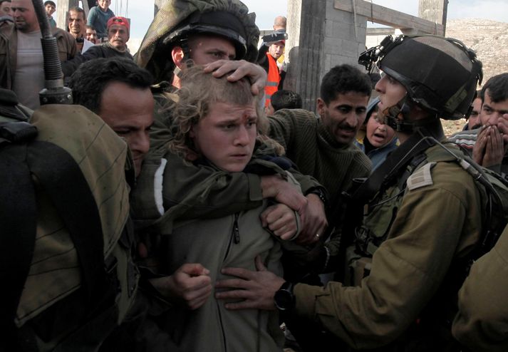 Ísraelskir hermenn taka við landtökumanni úr höndum Palestínumanna við Kúsra.