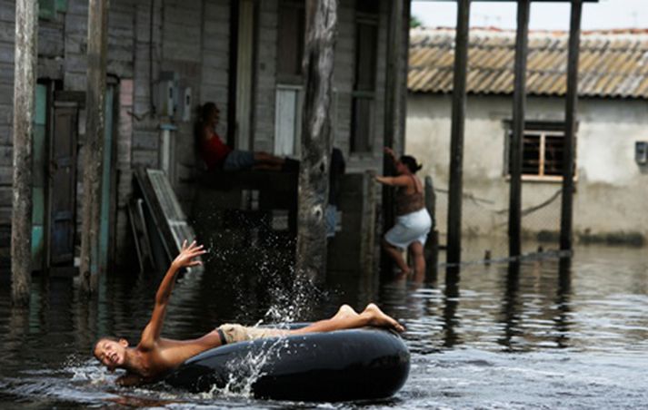 Götur á Kúbu eru sums staðar umflotnar vatni eftir yfirreið Ikes í síðustu viku en slíkt er ekki öllum á móti skapi, til að mynda ekki þessum dreng.