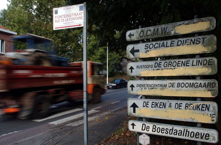 Vörubíll ekur hjá vegskiltum, þar sem búið er að krota yfir frönsk staðanöfn í Sint Genesius-Rode í flæmska hluta Belgíu.