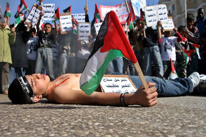 Palestínskur drengur heldur á fána og þykist dáinn á mótmælafundi gegn átökum fylkinga Fatah- og Hamas-liða í Rafah á Gaza í gær.