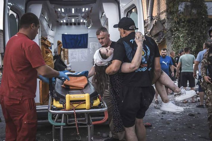 Karlmaður ber særða kona í sjúkrabíl eftir flugskeytaárás Rússa á Pokrovsk í Donetsk-héraði í gær