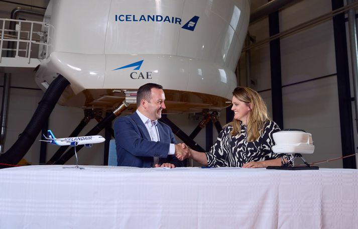 Sylvía Kristín Ólafsdóttir framkvæmdastjóri rekstrarsviðs Icelandair og James Cahill, aðstoðarframkvæmdastjóri farþegaflugsdeildar CAE handsala samninginn í þjálfunarsetri Icelandair í Hafnarfirði.