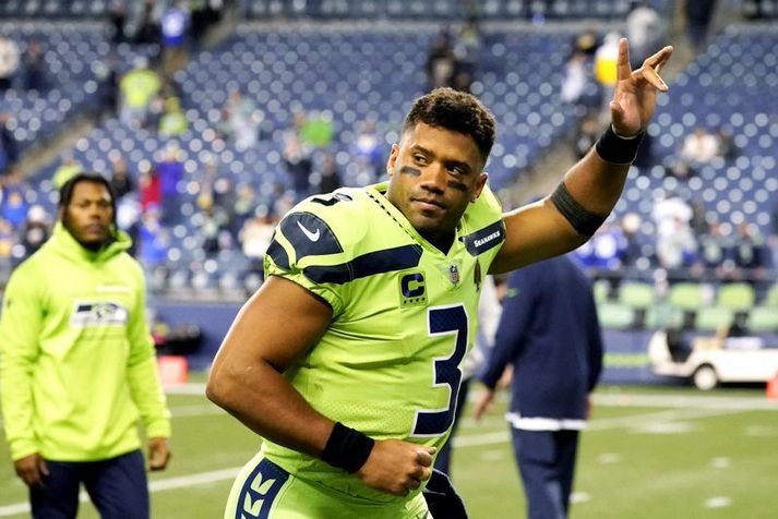 Russell Wilson veifar stuðningsmönnum Seattle Seahawks þegar hann yfirgefur völlinn meiddur á kasthendinni.