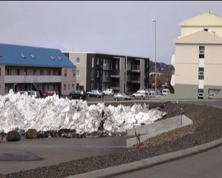 Fjölbýlishúsið sem um ræðir er við hliðina á húsinu með bláa þakinu.