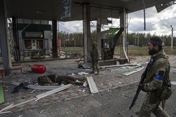 Úkraínskir hermenn og fallinn félagi þeirra í Lyman í norðanverðu Donetsk-héraði, en Rússar voru reknir þaðan um helgina. Góður árangur Úkraínumanna gegn Rússum hefur ekki verið þeim að kostnaðarlausu.