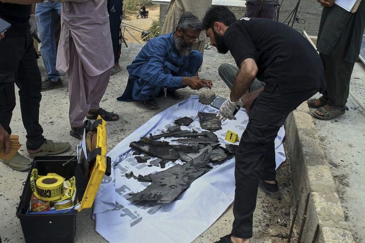 Pakistanskir rannsakendur safna brraki úr indverskum dróna í Karachi.