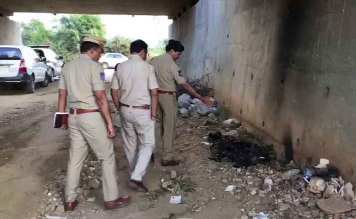 Lögreglumenn á vettvangi þar sem brennt lík konunnar fannst í Hyderabad.