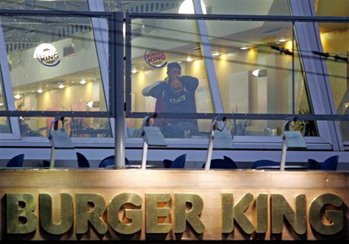 Annar byssumannanna heldur gísl við einn af gluggum Burger King í Istanbúl í dag.