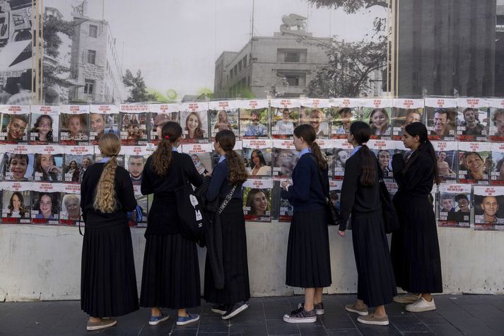 Ísraelskar stúlkur skoða myndir af þeim sem var rænt og eru í haldi Hamas.