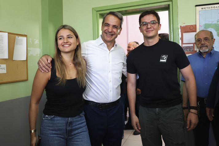 Kyriakos Mitsotakis, leiðtogi Lýðræðisflokksins fyrir miðju ásamt börnum sínum á kjörstað í Aþenu í dag.