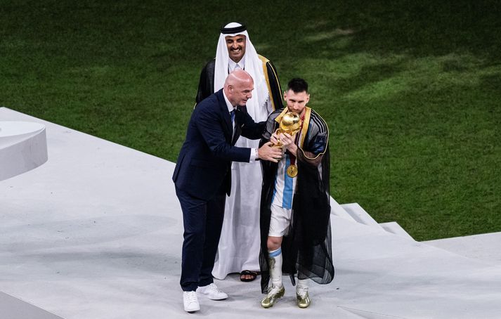 Gianni Infantino er búinn að afhenda Lionel Messi heimsbikarinn og er að stýra honum þangað sem sá argentínski átti að lyfta honum.