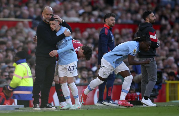 Pep Guardiola faðmar Phil Foden eftir að hann tók hann út af í leik Manchester United og Manchester City í gær.