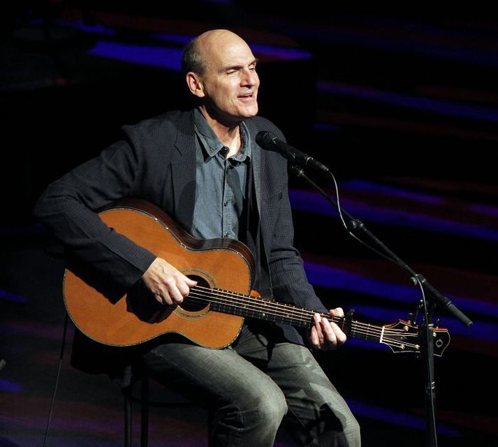 James Taylor með kassagítarinn uppi á sviði í Eldborgarsalnum.