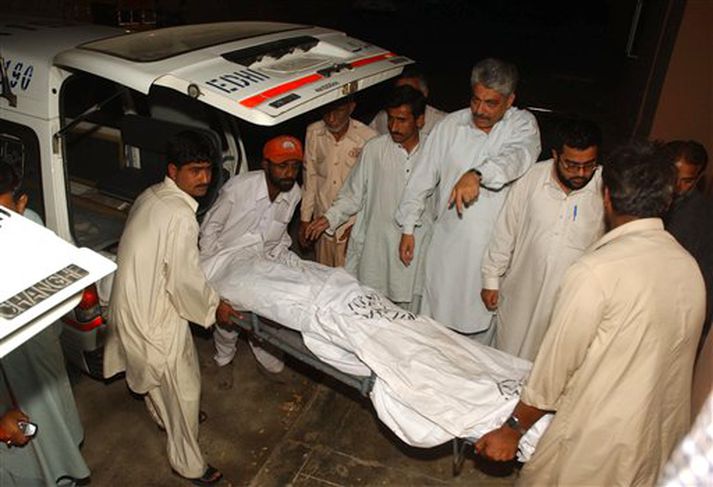 Sjúkrahússtarfsmenn bera líkið af einum Kínverjanna inn á sjúkrahús í bænum Hub í Pakistan.