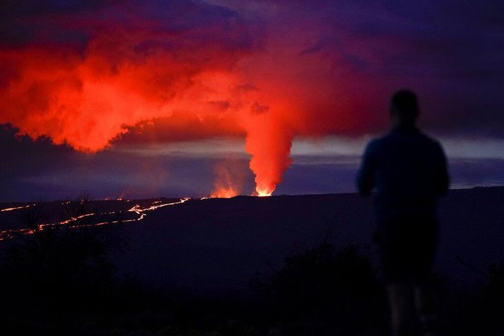 Maður fylgist með hrauni renna frá Mauna Loa-eldfjallinu á Stóru eyju Havaí.