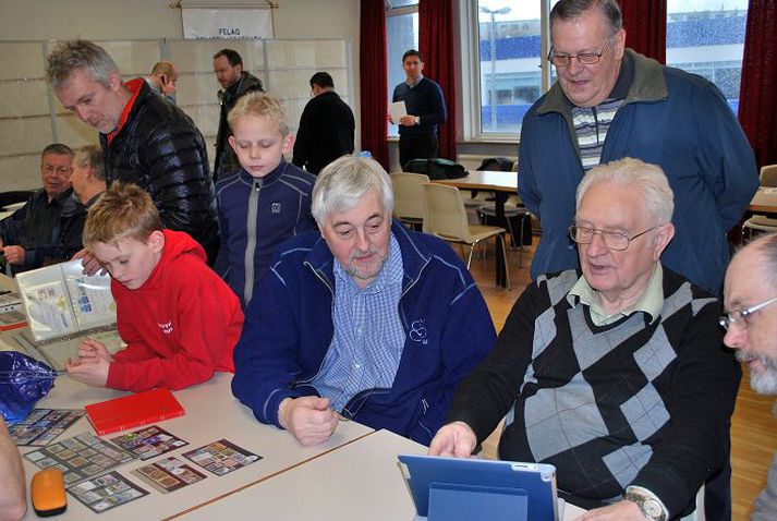 Viðar Ottesen horfir yfir öxlina á Hjalta Jóhannessyni með i-padinn. Ævar Petersen fylgist með. Við hlið hans er barnabarnið Matthías Ævar, sem safnar bara fuglamerkjum, og vinur hans Skúli, sem er líka frímerkjasafnari.