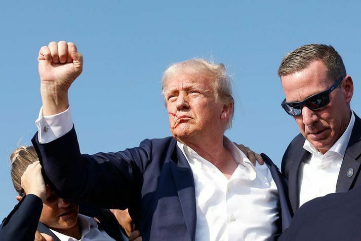 Trump og öryggisverðirnir þegar skotið hafði hæft hann í eyrað.