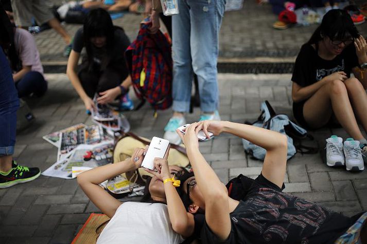 Mótmælendur í Hong Kong liggja á jörðinni á meðan þeir skoða símana sína. 
