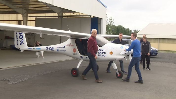 Rafmagnsflugvélin TF-KWH dregin út úr flugskýli Geirfugls í Fluggörðum síðdegis. Frumkvöðlarnir Friðrik Pálsson og Matthías Sveinbjörnsson draga vélina ásamt sænska flugkennaranum Rickard Carlsson, sem heldur um skrúfuna.