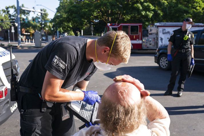 Sjúkraliði hugar að manni sem fékk hitaslag í borginni Salem í Oregon. Hitinn á svæðinu er meira en 16 gráðum yfir meðaltali þessa dagana.