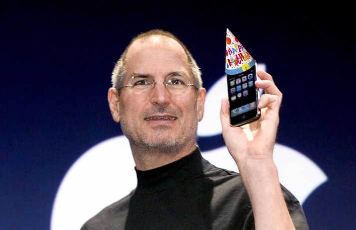 Steve Jobs með fyrstu gerð iPhone árið 2007. Athugið að afmælishattinum hefur verið bætt inn á myndina.