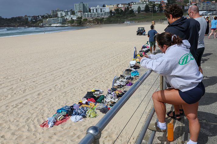 Fólk virðir fyrir sér persónulega muni sem urðu eftir á ströndinni þegar skotárásin hófst og fólk flúði.