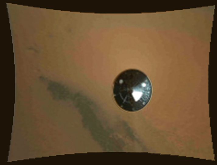 Hér má sjá hitaskjöld geimhylkisins sem flutti Curiosity til Mars. Myndin er tekin stuttu eftir að farið braut sér í gegnum gufuhvolf plánetunnar.