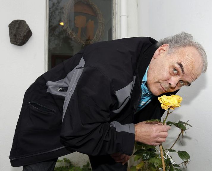 Pálmi Sveinsson dáist að blómstrandi rós í garði sínum.