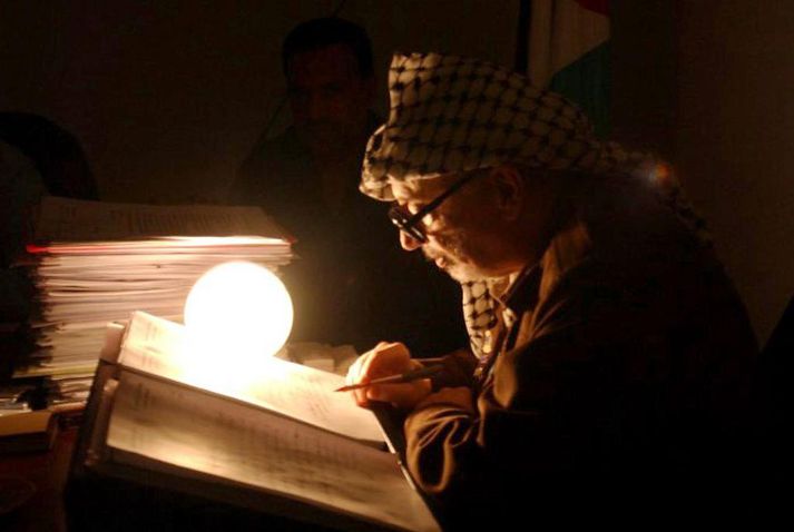Arafat blaðar í pappírum á skrifstofu sinni í Ramallah á Vesturbakkanum árið 2002, í miðju umsátri ísraelska hersins.