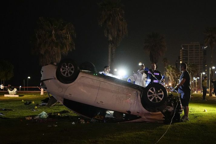 Ísraelsk lögregla stendur í kringum bílinn sem ökumaður keyrði inn í hóp túrista í Tel Aviv.